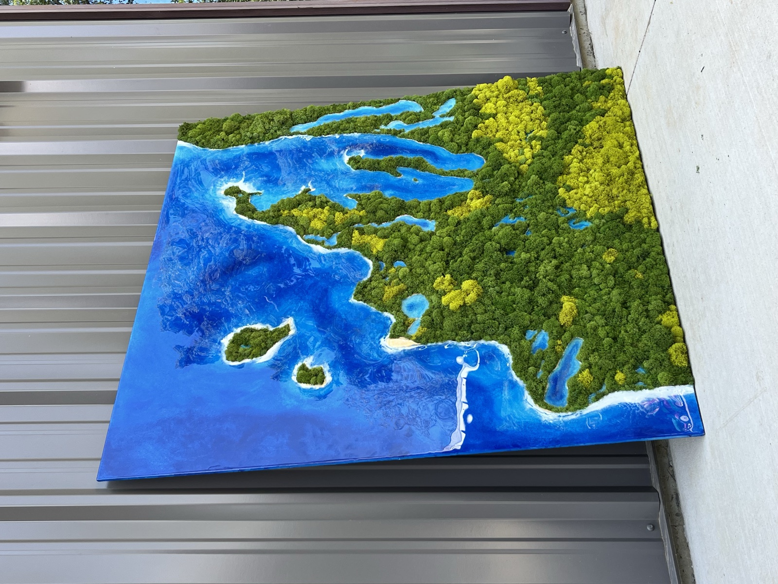 Aerial lake artwork in blue resin and green moss