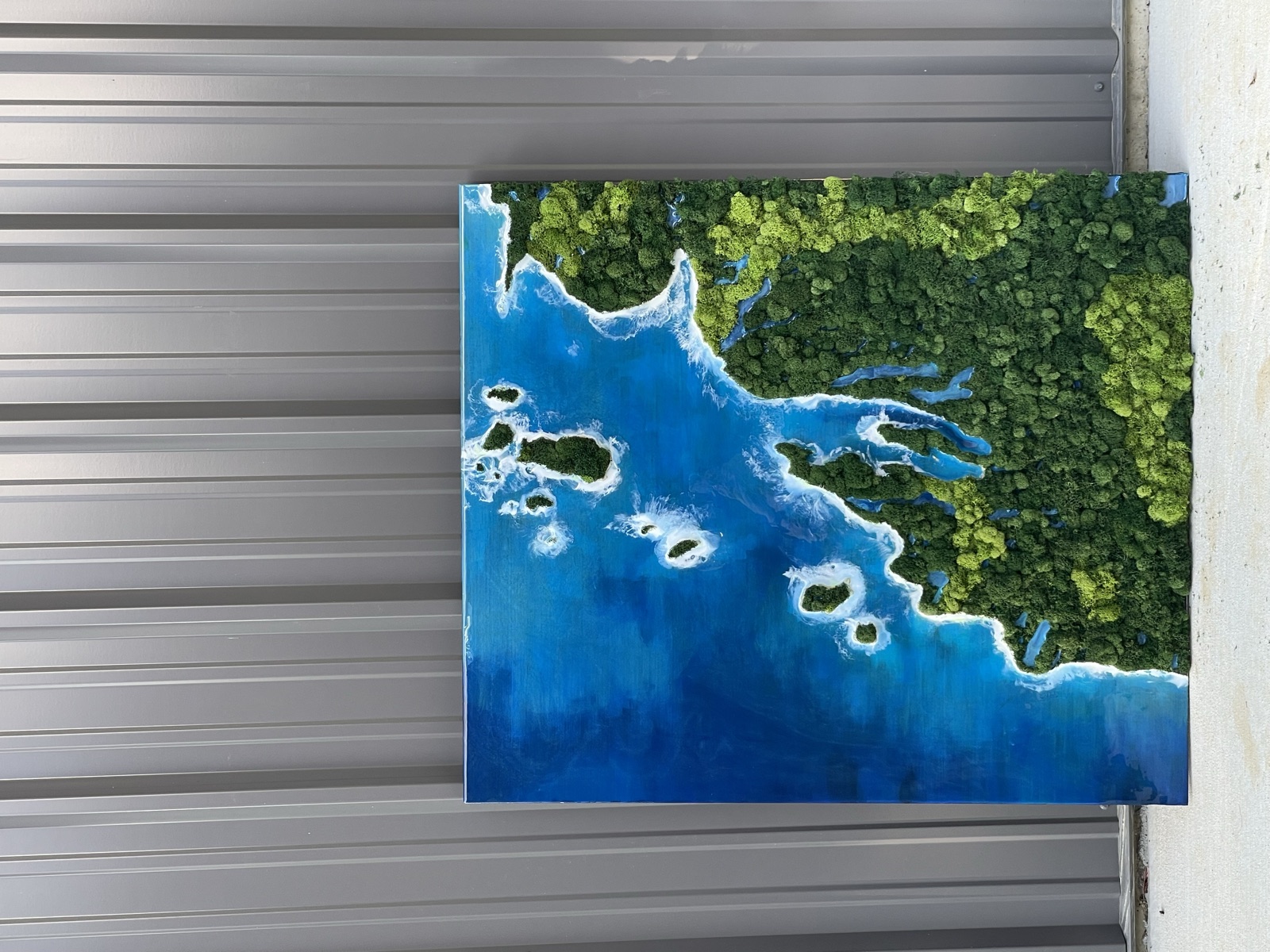 Aerial lake art with islands in blue resin and moss