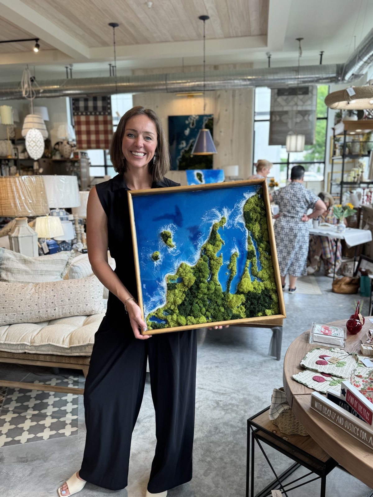 Anne holding a framed aerial lake artwork